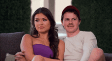 a man and a woman sitting on a couch looking at something