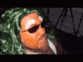 a man wearing sunglasses and a green wig looks at the camera