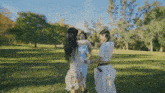 three women standing in a grassy field holding hands