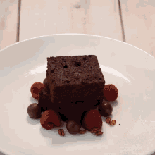 a white plate topped with a brownie berries and nuts