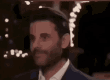 a man in a suit and tie is smiling while standing in front of a christmas tree .