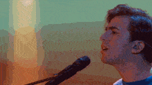 a man singing into a microphone with a rainbow background behind him