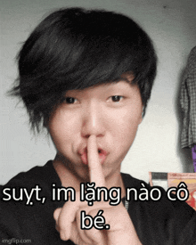 a young man is making a shhh gesture with his finger on his lips