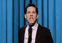 a man in a suit and tie is talking into a microphone .
