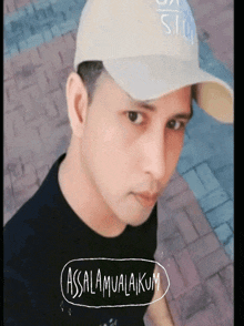 a man wearing a hat and a black shirt says ' assalamualaikum ' on the bottom