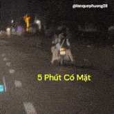 a group of people riding a motorcycle down a street at night .