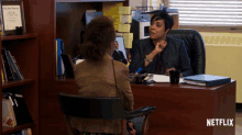 a woman sitting at a desk with a netflix logo on the bottom