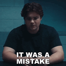 a man sits at a table with the words " it was a mistake " written on the bottom