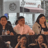 a group of people sit at a table in front of a store called arhouse