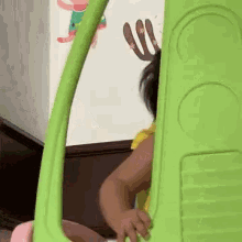 a baby is playing with a green toy car in a room .