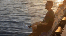 a man is sitting on a dock by the water .