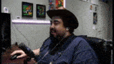 a man in a cowboy hat is sitting in front of a microphone