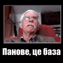 an elderly man with glasses and a mustache is sitting in a red chair .