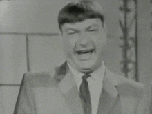 a man in a suit is making a funny face