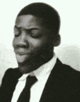 the man is wearing a suit and tie and making a funny face .