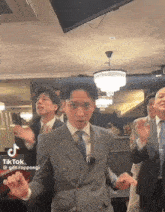 a group of men in suits and ties are dancing in a room