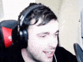 a man wearing headphones with the letter g on the back sits in a chair