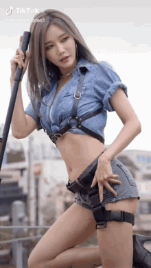 a woman in a denim shirt and shorts is holding a rifle .