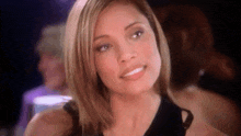 a woman in a black dress looks at the camera and smiles