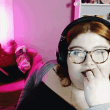 a woman wearing glasses and headphones with a pink light in the background