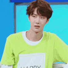a young man wearing a green t-shirt with a white collar is making a funny face .