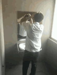 a man in a white shirt is standing in front of a mirror