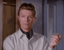 a man in a white shirt is smoking a cigarette .