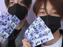 two men wearing face masks are holding purple stickers in front of their faces
