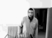 a man in a hooded jacket is standing in a room .