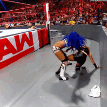 two women wrestling in front of a sign that says raw on it