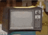 an old television is sitting on top of a table with a piece of paper on top of it .