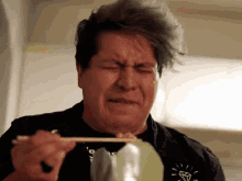 a man is eating food with chopsticks and making a face