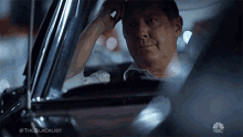 a man is sitting in a car with #theblacklist on the bottom right