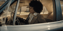 a woman in a suit is sitting in a car