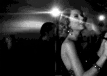 a black and white photo of a woman dancing in a club .