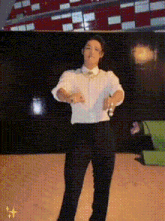 a man in a white shirt and black pants is dancing in front of a checkered wall .