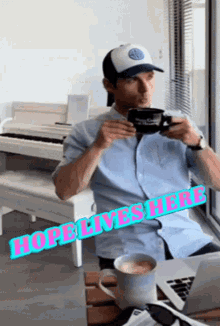 a man sitting at a table with a cup of coffee and a sign that says hope lives here