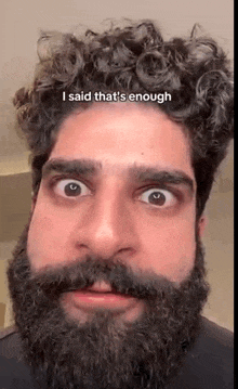 a man with a beard and curly hair is making a face .