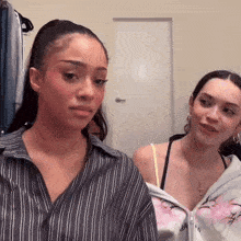 two young women are standing next to each other in a room .