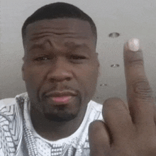 a man with a beard and a white shirt is giving the middle finger