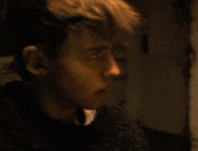 a close up of a young man 's face with a sweater on