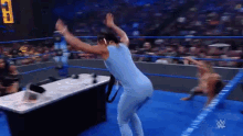 a female wrestler is dancing in a wrestling ring while another wrestler is falling .