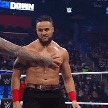a shirtless wrestler is being held by another wrestler in a ring