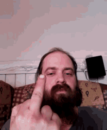 a man with a beard is giving the middle finger to the camera