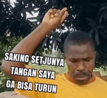 a man wearing a yellow shirt is holding his fist up in the air