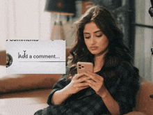 a woman is sitting on a couch looking at her phone with a message that says " add a comment "
