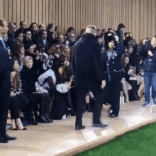 a crowd of people watching a fashion show with a woman taking a picture of herself