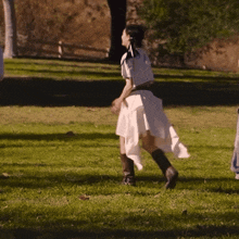 a woman in a white skirt and boots is running in a park