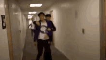 a group of people are walking down a hallway .