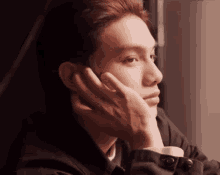 a close up of a person 's face with their hand on their chin